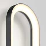 A close-up of a modern, oval-shaped wall light fixture with a black frame and a glowing white LED strip, mounted on a light gray wall.