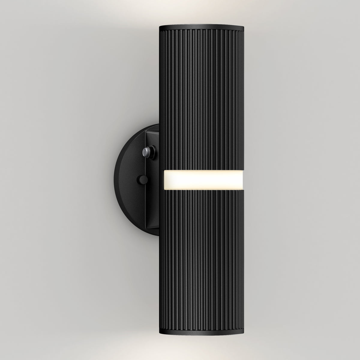 A modern black wall sconce with a ribbed cylindrical design, mounted on a round base, emits light from a central horizontal strip and both the top and bottom. The fixture is attached to a plain light-colored wall.