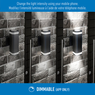 Three Stark modern LED indoor-outdoor lights by Artika are mounted on a brick wall, each at different brightness levels. The text explains you can adjust the light’s intensity via a mobile app. DIMMABLE (APP ONLY) appears below.