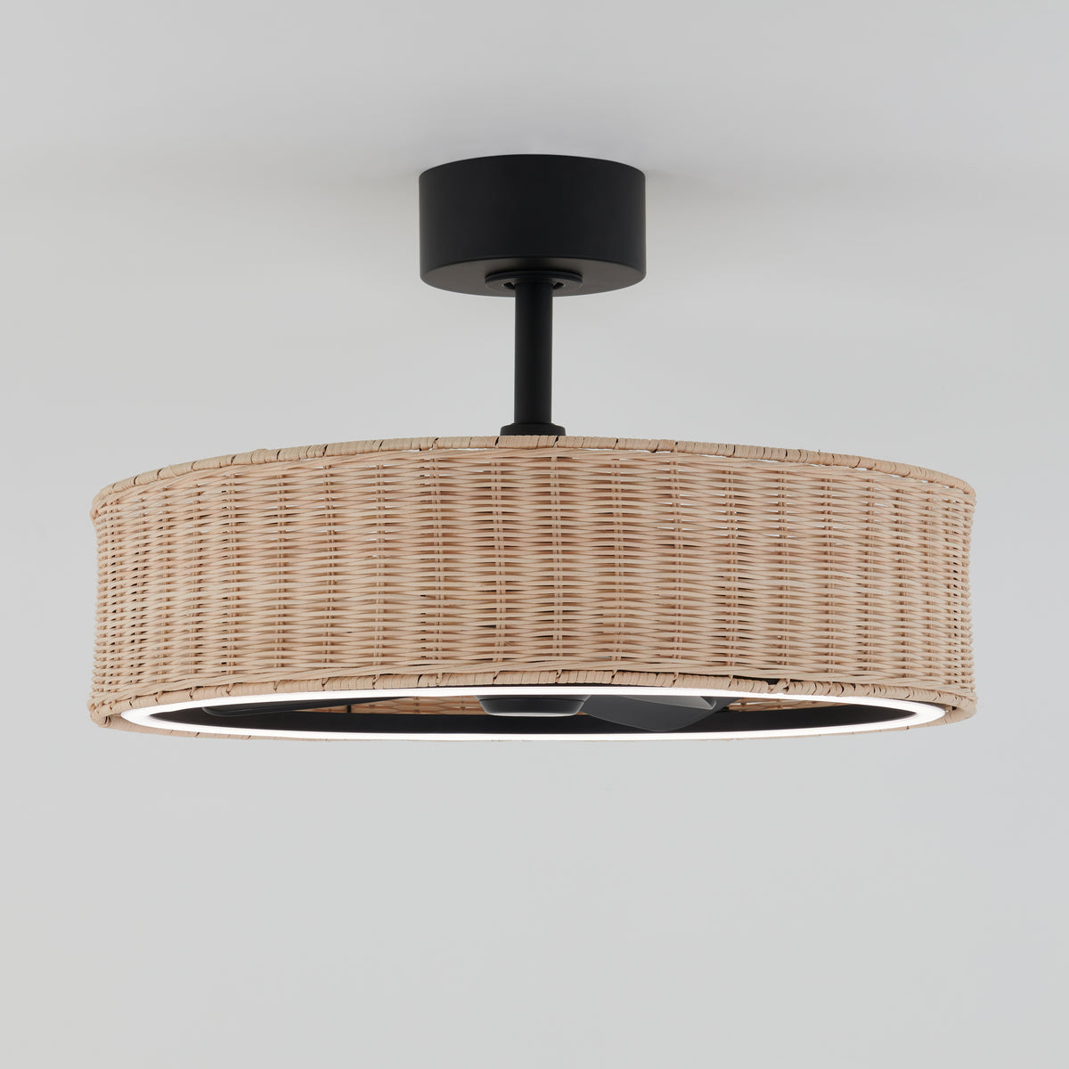 A ceiling-mounted light fixture with a wide, cylindrical woven rattan shade and a black metal base, set against a plain white background.