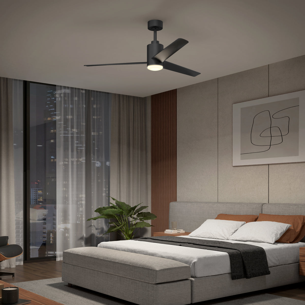 A modern bedroom with a large bed, gray upholstered headboard, blanket, and pillows, a ceiling fan with a light, abstract wall art, a plant, and a large window showing a city skyline at night.