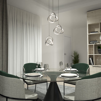 Modern dining room featuring a round glass table for four, green and gray chairs, and the Artika Zephyr 3-light LED pendant overhead, with sheer curtains and shelving in the background.
