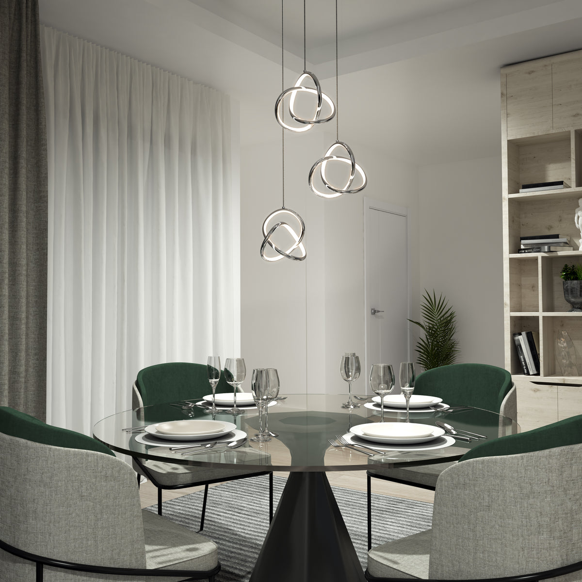 Modern dining room with a round glass table set for four, green and gray chairs, sculptural pendant lights above, white curtains, and shelves with decor in the background.
