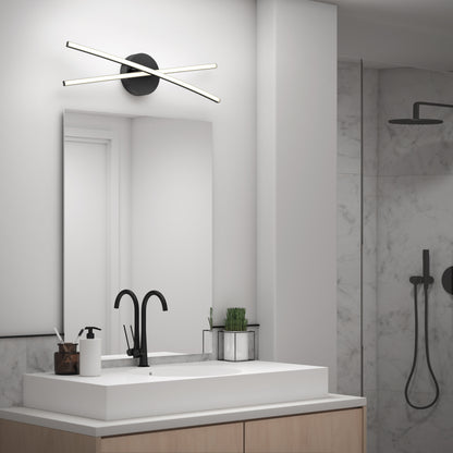 Modern bathroom features a rectangular white sink, black faucet, soap dispenser, and plant on a light wood vanity. Above the mirror is the Artika Orly modern LED bathroom vanity light 3 CCT. Marble shower with black fixtures is visible in back.