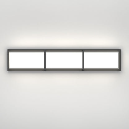 The Artika Subway LED bathroom vanity light features three illuminated panels in a dark frame, mounted on a white wall, emitting a gentle glow above and below.