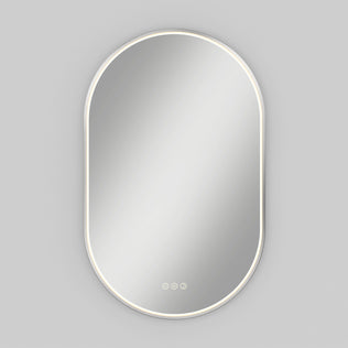 Artika Royce LED mirror 3 CCT with defogger, oval-shaped with white frame, illuminated and mounted on a light gray wall.