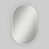 Oval-shaped wall mirror with a thin, illuminated LED light border, mounted against a plain light gray background. Three small touch buttons are visible at the bottom center of the mirror.