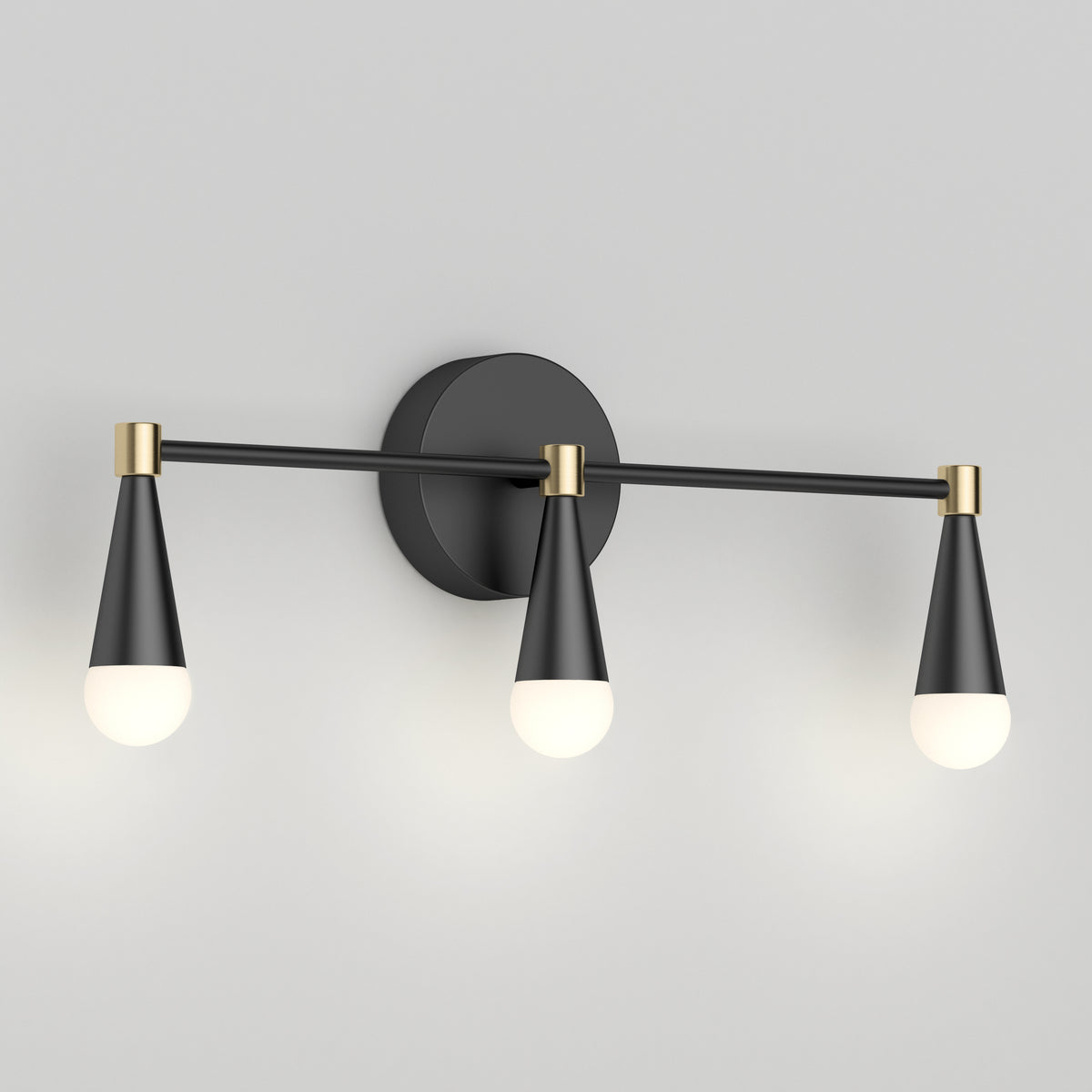 A modern wall sconce with three cone-shaped black and gold light fixtures, each holding a round white bulb, mounted on a circular black base.
