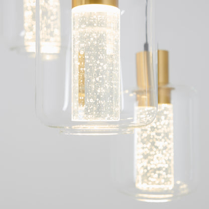 Close-up of the Artika Champagne Globe 4-light LED pendant, featuring clear cylindrical glass shades with gold accents. The illuminated bulbs display decorative bubbles, producing a sparkling effect against a plain background.