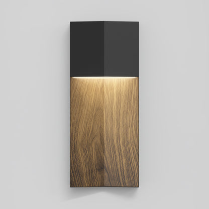 The Artika Howel modern LED indoor-outdoor wall light 5 CCT features a black top, natural wood grain lower section, and emits warm downward light. Shown on a plain, light gray wall.