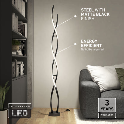 The Artika Swirl modern LED floor lamp, featuring a matte black steel finish and twisting light strips, stands beside a gray sofa and bookshelf. Text highlights its energy efficiency and included 3-year warranty.
