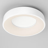 A modern, circular white ceiling light fixture with a minimalistic design, mounted on a light gray ceiling. The fixture emits a soft, even glow from its inner ring.