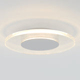 A modern circular ceiling light with a translucent, glowing ring and a solid central disc, mounted on a smooth white ceiling. The light creates soft, concentric shadows on the ceiling.