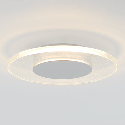 The Artika-CAN-dev Essence Disk LED flush mount features a modern circular design with a glowing haloed glass diffuser and solid central disc, offering soft, diffused light and subtle shadows on the ceiling.