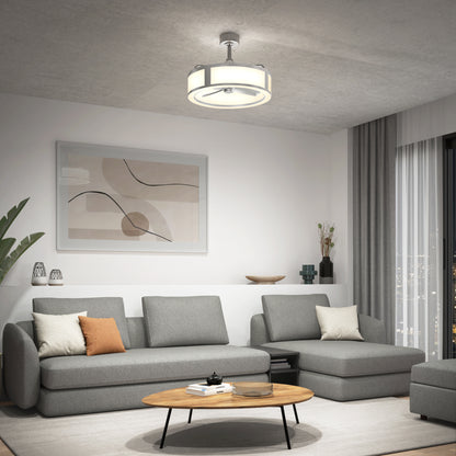 Modern living room with gray sectional sofas, a round wooden coffee table, abstract wall art, and the Artika Huxley 23 in. LED modern ceiling fan (3 speeds). Large windows with curtains and decorative plants create a cozy, stylish atmosphere.