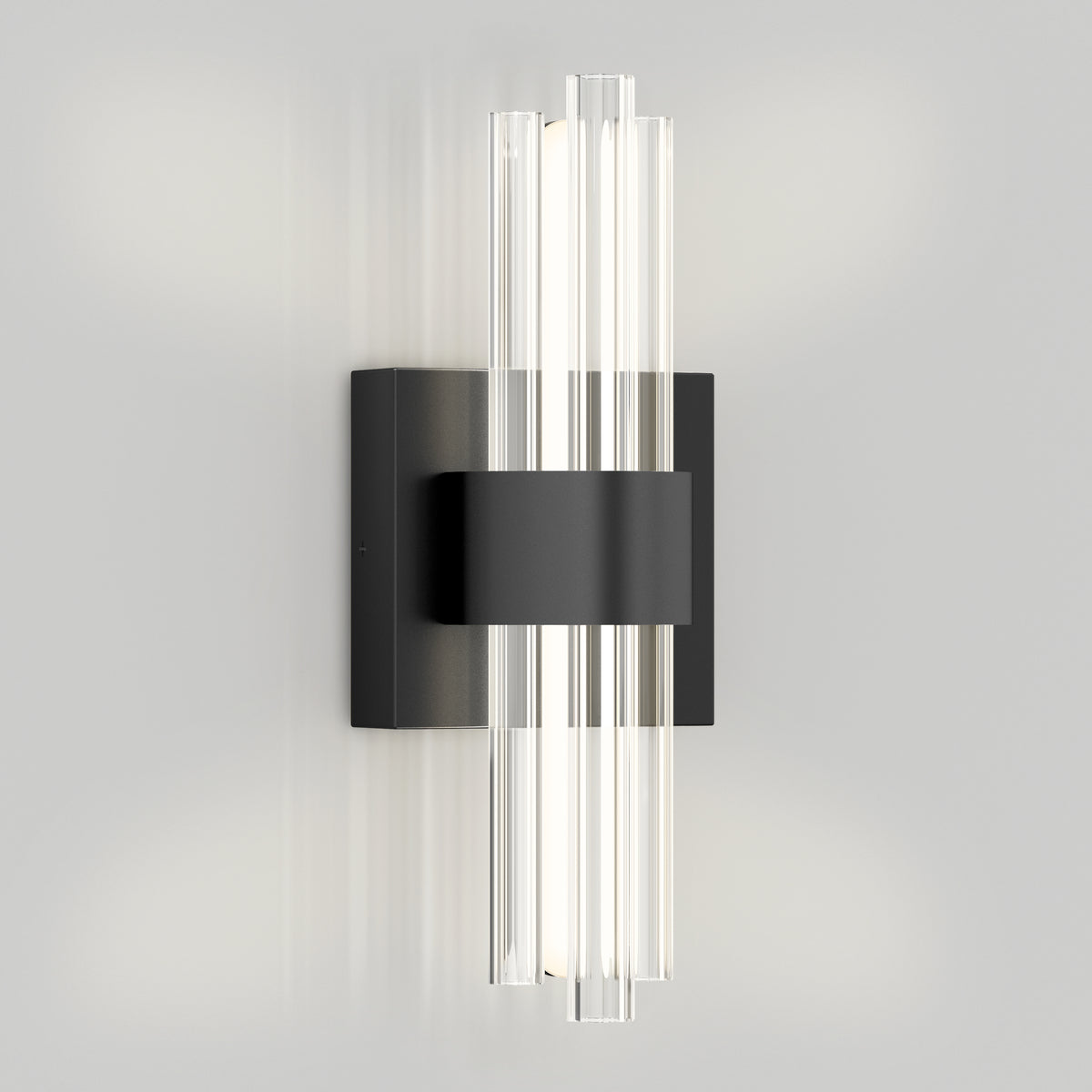 A modern wall sconce with a black rectangular base and central band, featuring vertical glass rods on both sides that diffuse the light, mounted on a light grey wall.