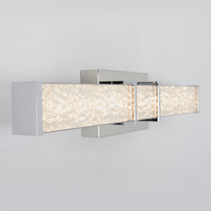 The Artika Royale LED bathroom vanity light features a chrome finish and two rectangular bars with textured, crystal-like accents, casting a soft white glow—perfect for modern spaces.