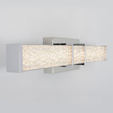 A modern wall-mounted light fixture with two rectangular, chrome-finished bars filled with textured, crystal-like material, emitting a soft, bright glow against a light gray wall.