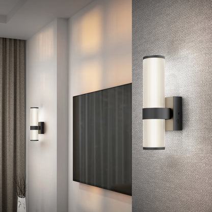Modern living room with two Artika Mirado modern LED wall sconce 5 CCT fixtures, a large flat-screen TV, textured wallpaper, and floor-length curtains. Warm light from the sconces gently illuminates the space.