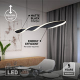 Modern dining room with a sleek, curved matte black LED pendant light, labeled as adjustable height, energy efficient, no bulbs required, and 5-year warranty. A table is set beneath with plates, glasses, and napkins.