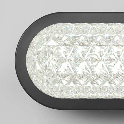 A close-up of the Artika Carat LED contemporary bathroom vanity light with a black frame and textured crystal-like glass, emitting bright white light; features 3 CCT settings.
