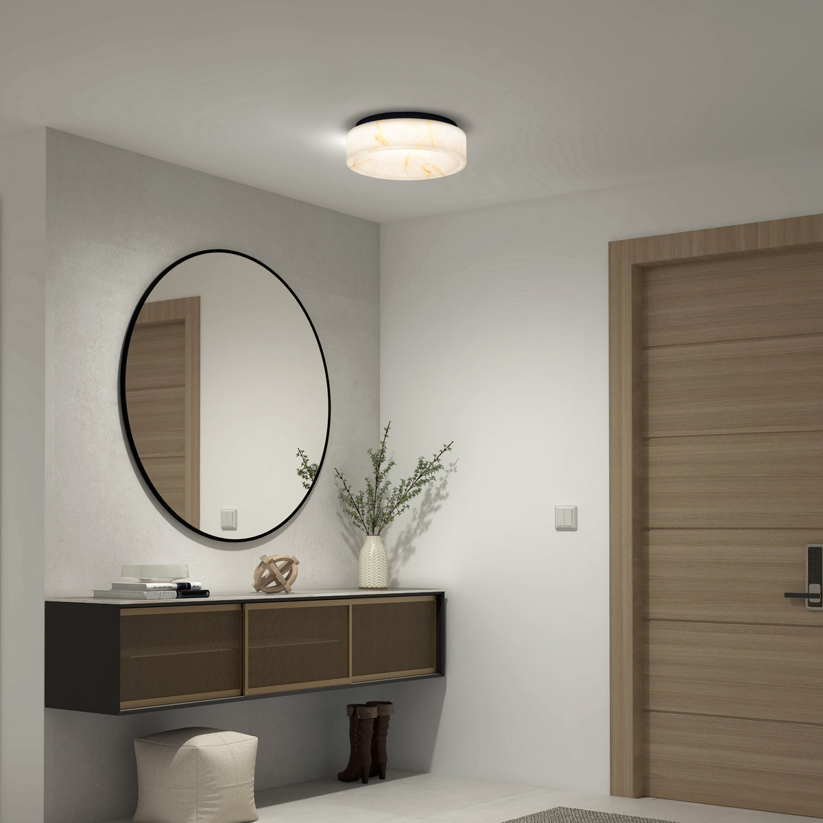 A modern entryway features a round mirror above a floating cabinet, a vase with greenery, decor accents, boots below, and is illuminated by the Artika Clifford 15 in. flush mount light 5 CCT.