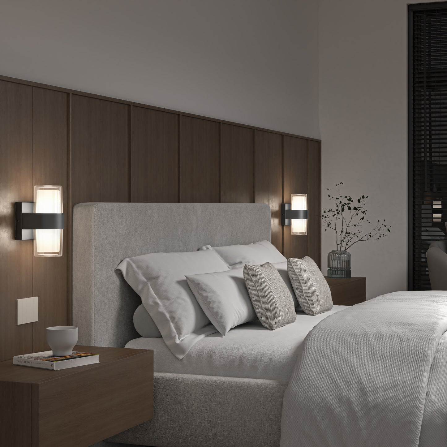 Modern bedroom with a grey upholstered bed, white bedding, and pillows. Wooden nightstands with a cup and vase sit beside the bed; Artikas Colton modern LED indoor-outdoor wall lights and a glass vase with branches decorate the space.