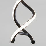 A close-up of a modern, spiral-shaped LED light fixture with two intertwined black and white bands against a plain gray background.