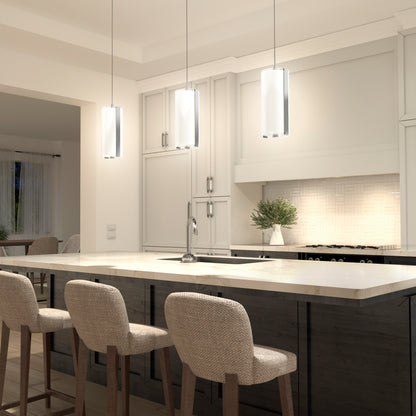 A modern kitchen features three Artika Subway Round Mini LED pendant lights above a marble island with three cushioned bar stools, light cabinets, a built-in stove, and a small potted plant on the counter.