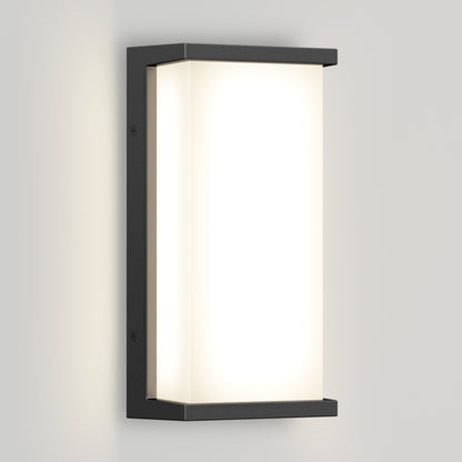 The Artika Faro modern LED indoor-outdoor wall light 3 CCT features a rectangular black metal frame and frosted white diffuser, emitting soft warm light on a light-colored wall.