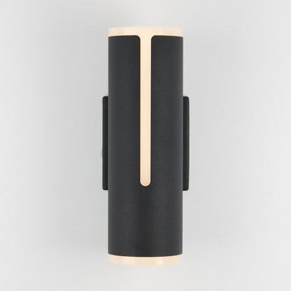 The Artika Linea modern indoor-outdoor LED wall light is a sleek black cylindrical sconce, emitting soft warm light from the top, bottom, and a front vertical strip, shown mounted on a light gray wall.