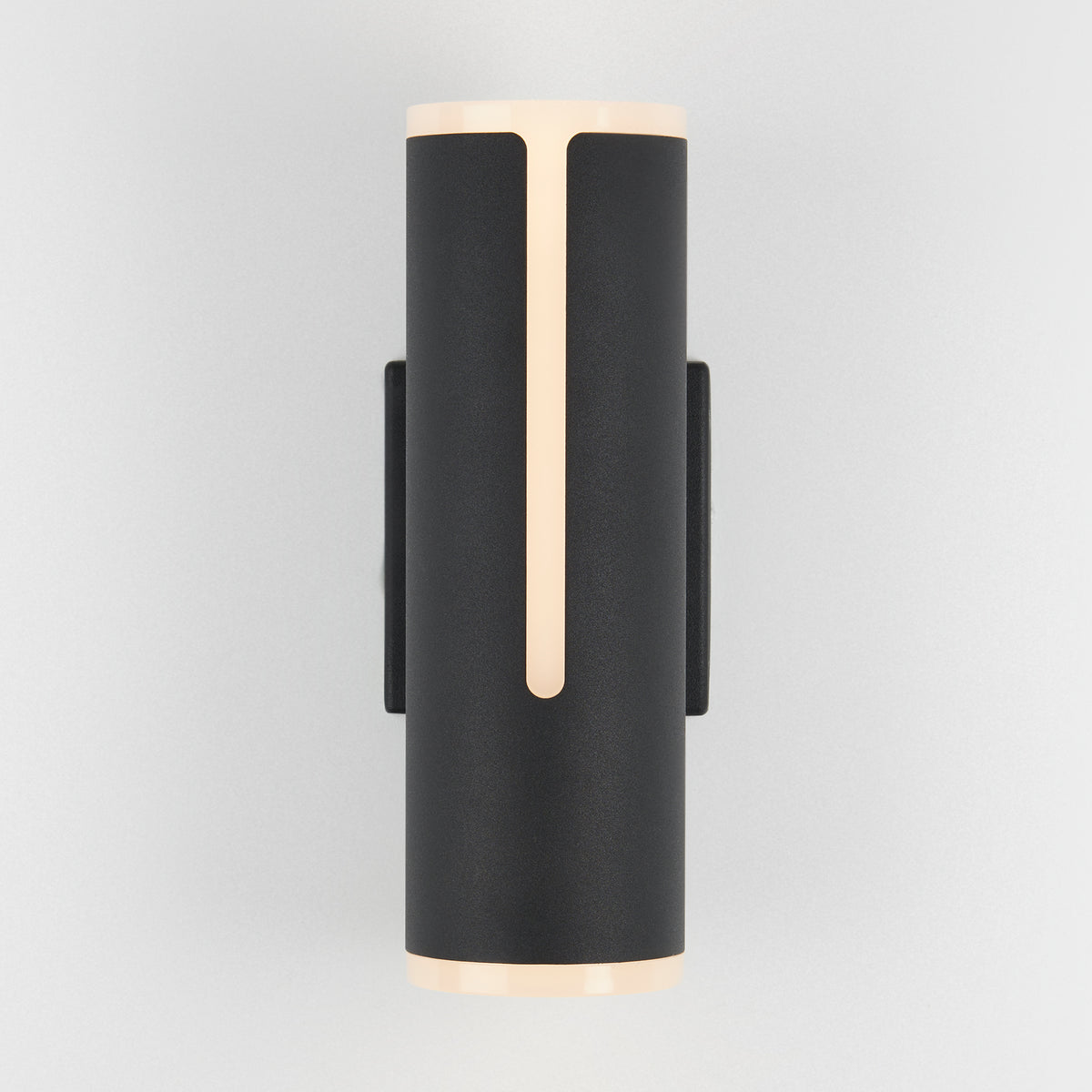 A modern cylindrical black wall sconce with narrow vertical light strips on the front and soft glow at the top and bottom, mounted on a light grey wall.