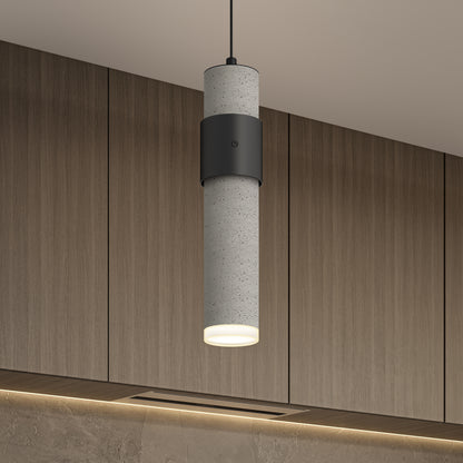 The Artika Barden 3-light LED pendant light features a modern cylindrical design with concrete texture and black accents, hanging in front of wood-paneled cabinets and casting a warm downward glow.