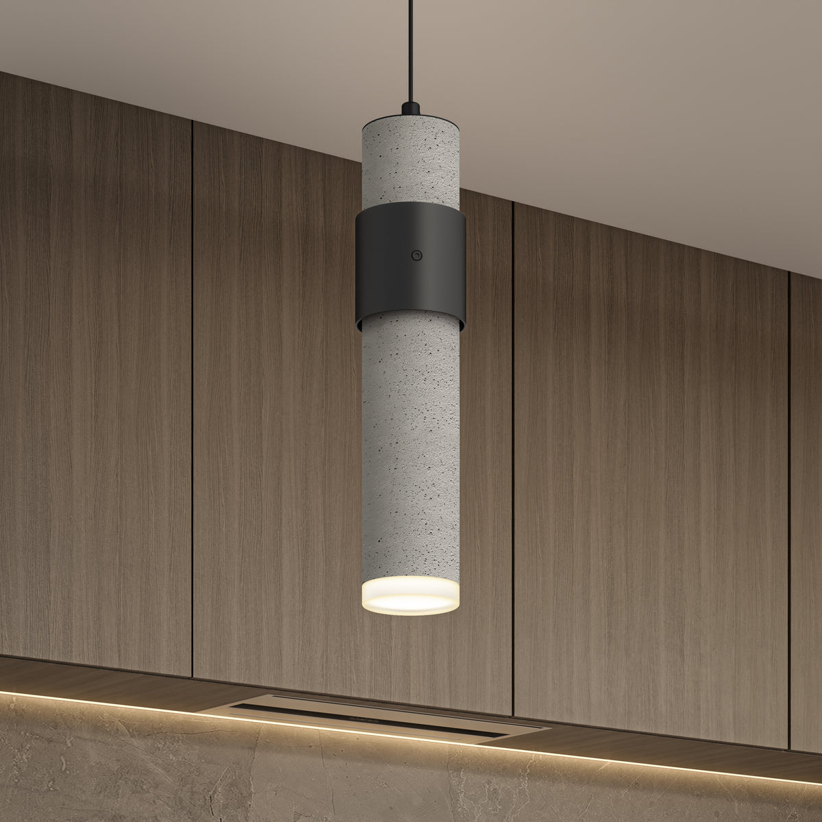 A modern cylindrical pendant light with a concrete finish and black accent hangs from the ceiling in front of wooden cabinets with subtle lighting below.