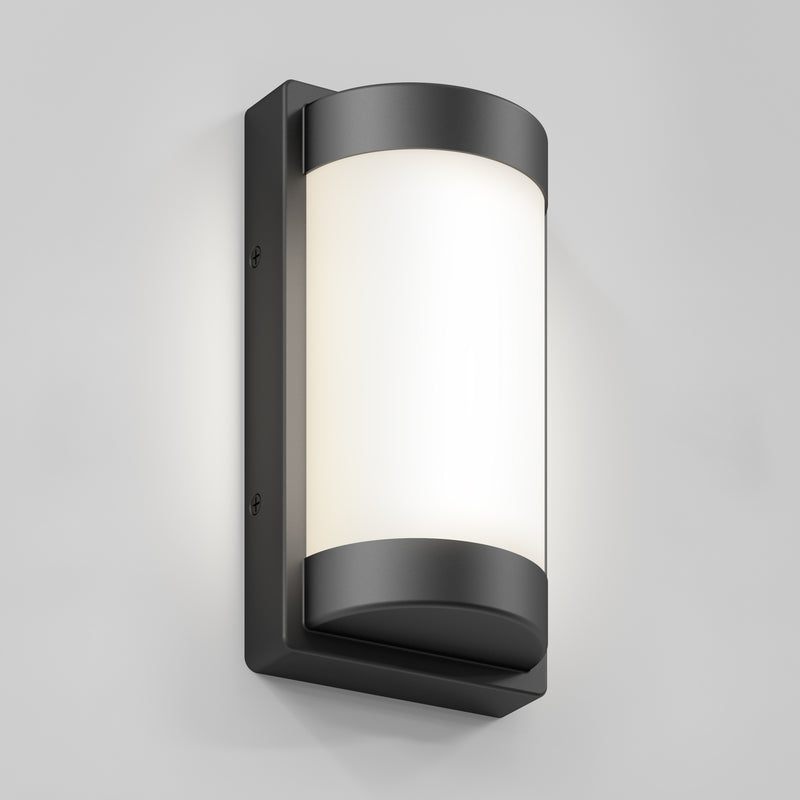 The Artika Fogo modern LED indoor-outdoor wall light 5 CCT features a cylindrical frosted white shade and black metal frame, mounted on a light gray wall.