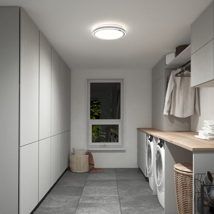 Modern laundry room with gray cabinets, wood countertop, washer, dryer, hanging clothes, baskets, and a window with greenery. Brightly lit by the Artika Altitude 15 in. LED modern flush mount light (5 CCT).