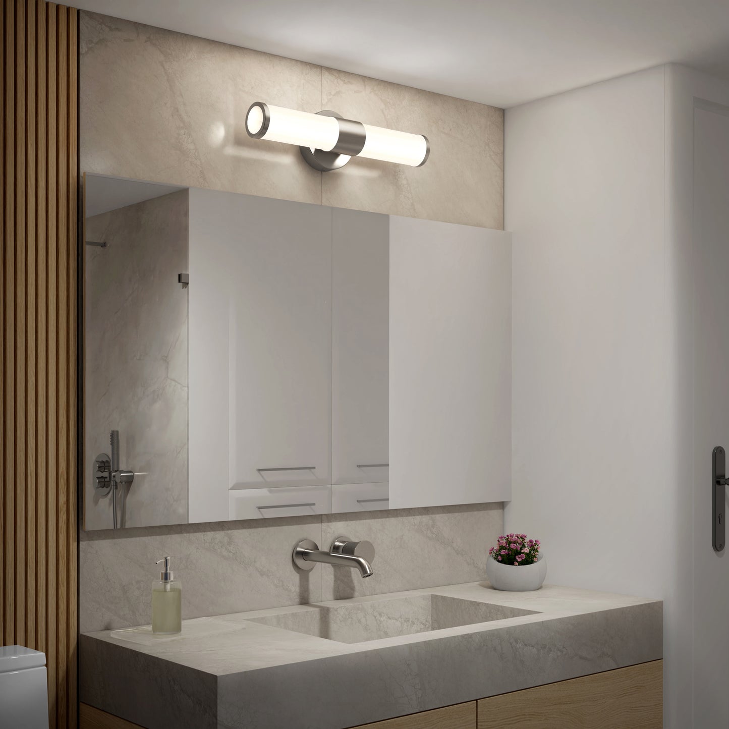 A modern bathroom features a large mirror, rectangular sink, wall-mounted faucet, soap dispenser, small plant bowl, and is illuminated by the Artika Adina modern bathroom vanity light 3 CCT above the mirror.