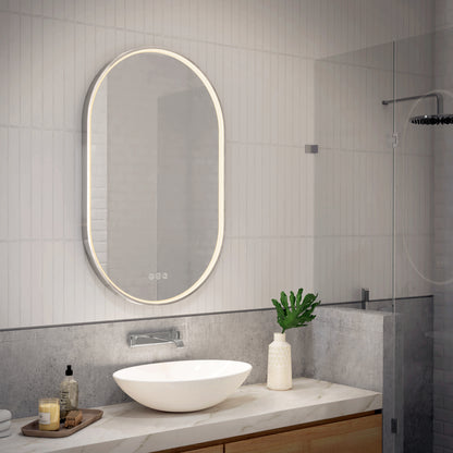 Modern bathroom featuring the Artika Royce LED mirror 3 CCT with defogger above a white vessel sink, accompanied by a soap dispenser, decorative plant, and bottle on a marble countertop; glass shower enclosure is visible to the right.