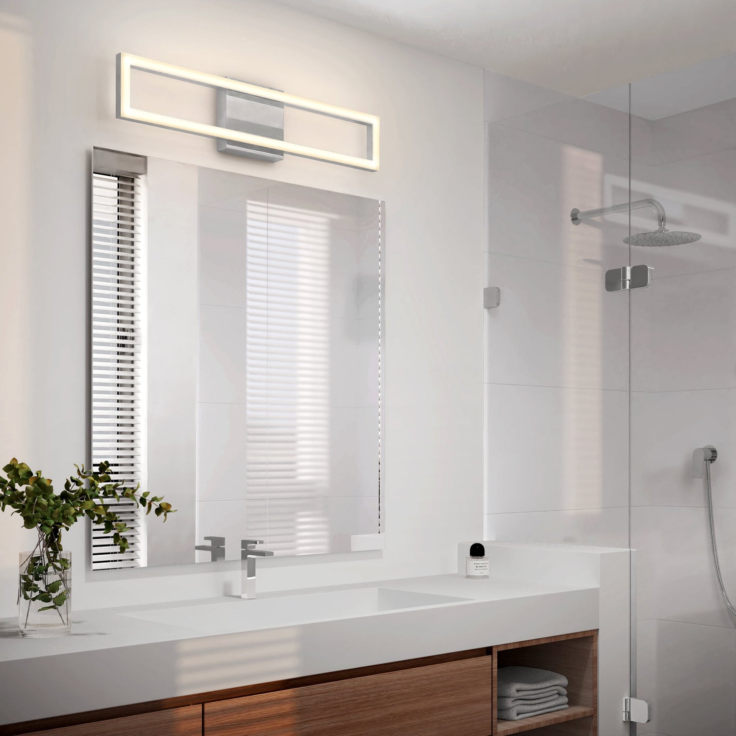 Modern bathroom with a large mirror, Artika-CAN-dev Dover modern LED bathroom vanity light 5 CCT above it, white sink with chrome faucet, wooden cabinet below, glass-enclosed shower in the background, and a small plant on the countertop.