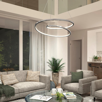 Modern living room with gray sofas, armchairs, a glass coffee table, and the Salto LED pendant light by Artika with a chrome finish hanging from a high ceiling. Large windows, sheer curtains, and a potted plant complete the contemporary look.