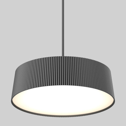 The Artika Groove Drum LED contemporary pendant light features a wide, cylindrical, dark gray ribbed shade and 3 CCT options, hanging from the ceiling and casting a bright, even glow against a plain gray background.