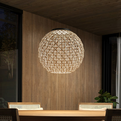 The Artika Benson LED pendant light 5 CCT hangs above a wooden dining table with chairs in a modern room featuring wood-paneled walls, large windows, and a potted plant in the corner.