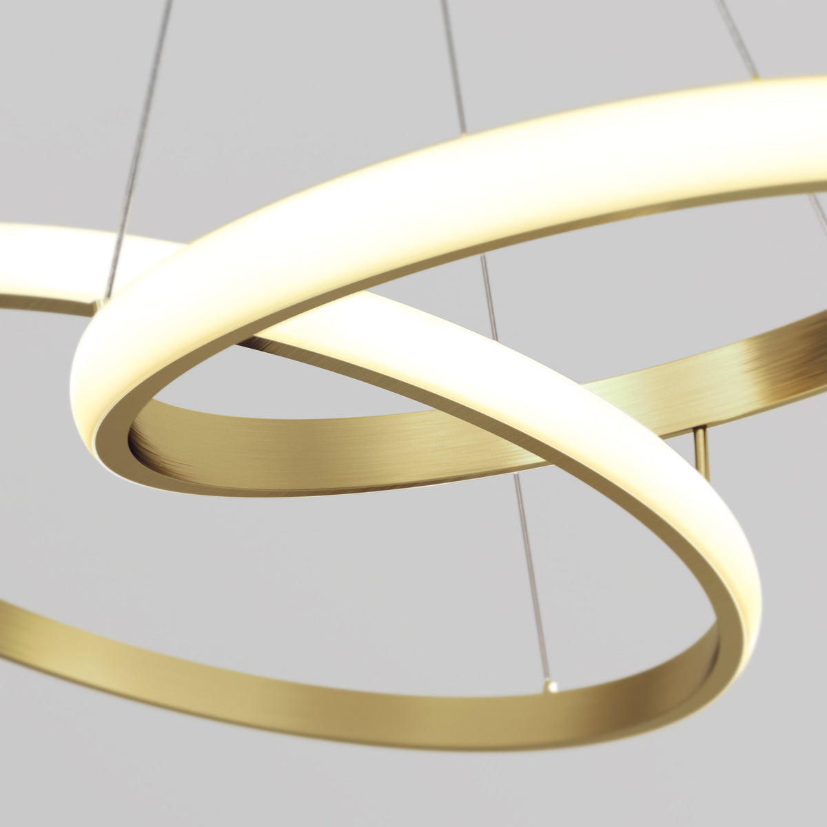 Artika’s Mora 28″ LED Pendant features dimmable, intertwined gold rings as a modern chandelier against a light background.