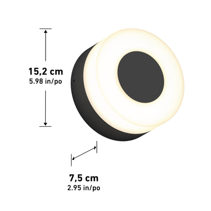 The Artika Ludwig modern LED indoor-outdoor wall light 5CCT features a round black center and outer section with a white illuminated ring, measuring 15.2 cm (5.98 in) in diameter and 7.5 cm (2.95 in) deep.