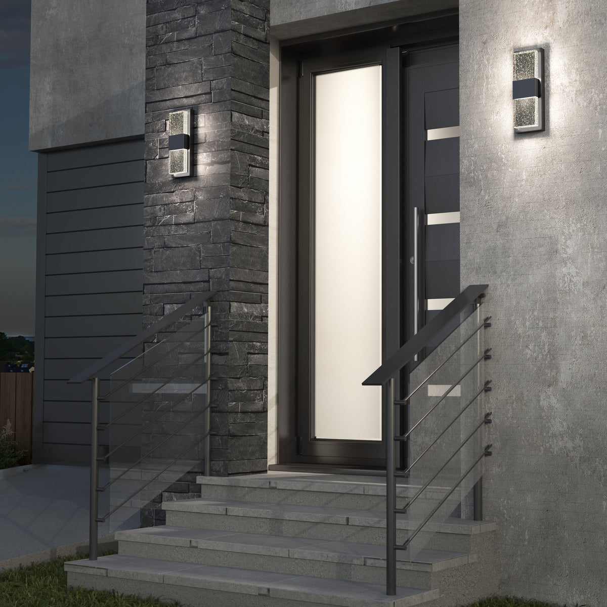 A modern front door with frosted glass panels, illuminated by two wall-mounted outdoor lights. Gray stone and concrete exterior, metal railings, and steps lead up to the entrance.