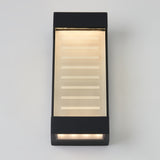 A modern rectangular black wall light fixture with a frosted glass panel, emitting a warm glow. Horizontal lines are etched on the glass, and light shines from both the top and bottom edges.