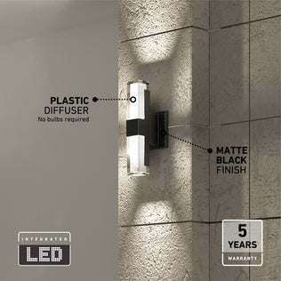 The Artika Gemini indoor-outdoor LED wall light is shown illuminated on a textured wall, featuring a matte black finish and plastic diffuser. Labels highlight No bulbs required and 5 years warranty.