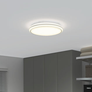 The Artika Emina 13 in. LED flush mount light 3 CCT glows on a white ceiling above dark gray cabinets and shelves; folded towels and a window with blinds complete the modern look.