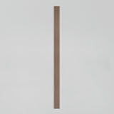 A single vertical wooden slat with evenly spaced grooves stands centered against a plain, light gray background.