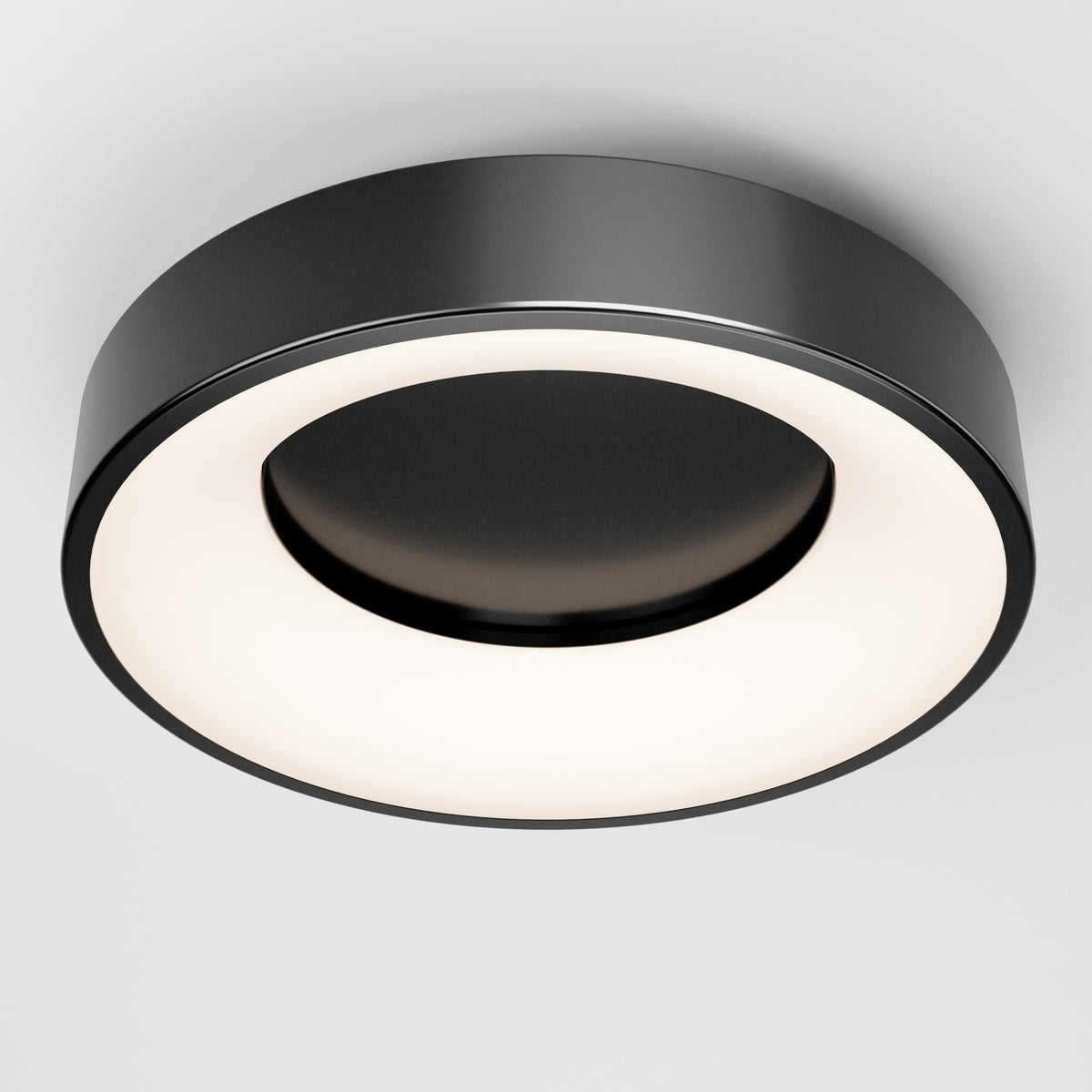 A modern, round ceiling light fixture with a black outer ring and a glowing circular white center, mounted on a white ceiling.